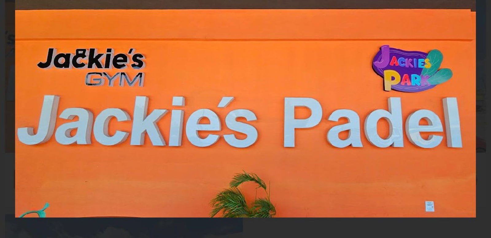 Vibrant exterior signage of Jackie's Padel and Gym on orange wall Costa del Este Panama