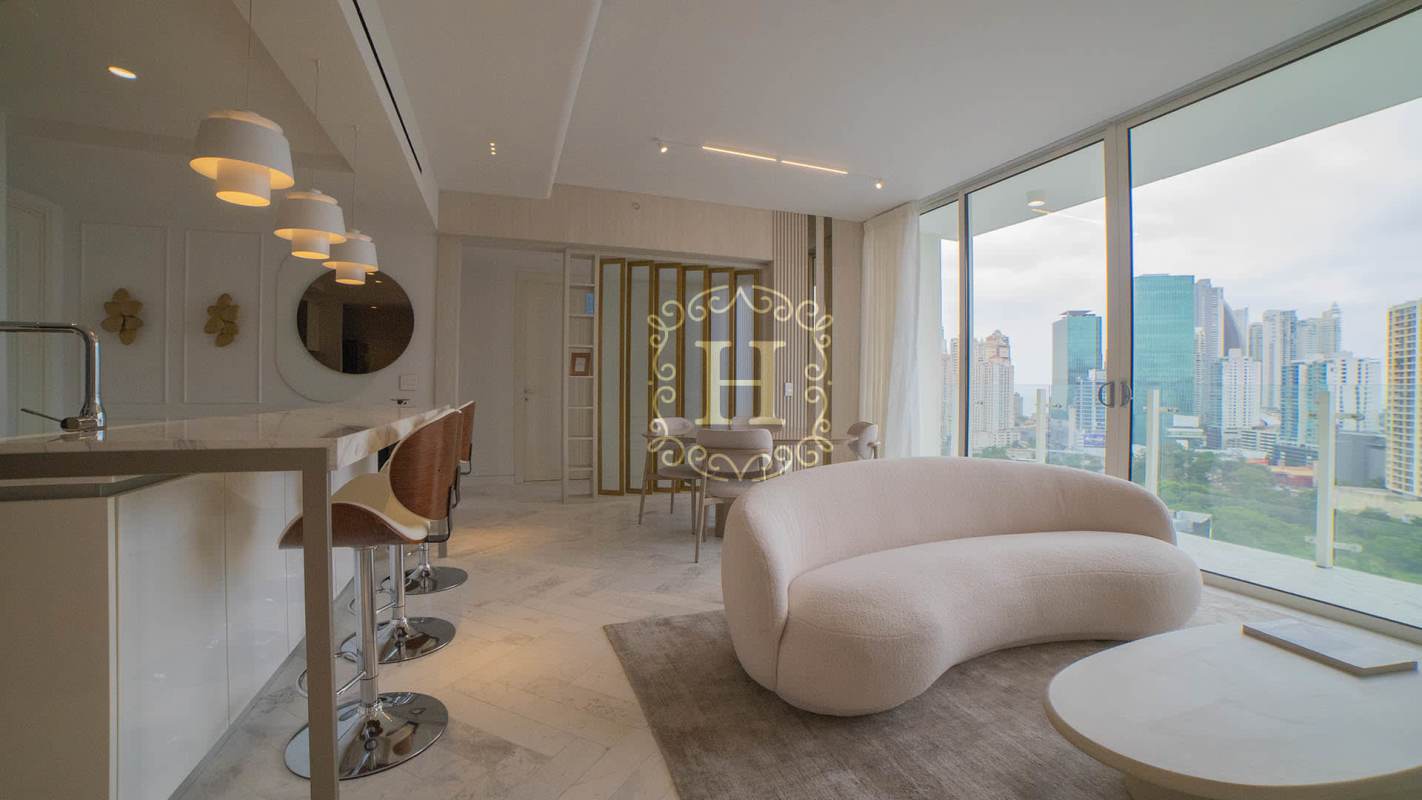 Bright living room with curved sofa and ocean view windows at PH Yacht Club Tower in Marbella Panama