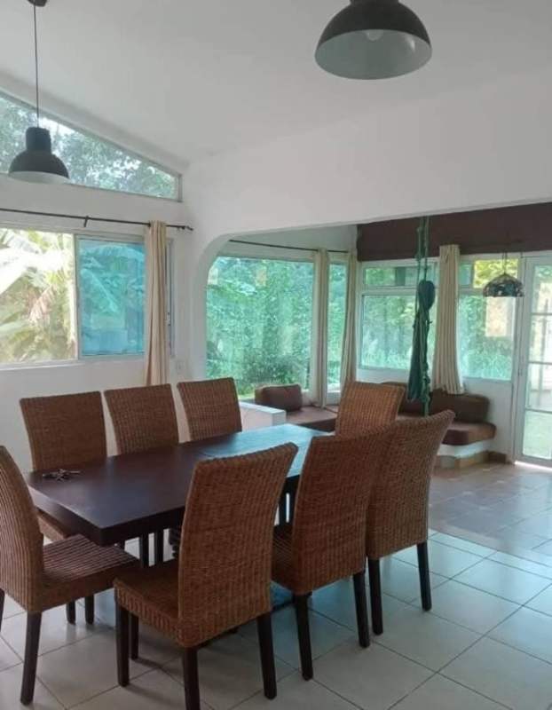 Dining room with rattan chairs, sunroom, panoramic garden views in country house Cerro Azul Panama