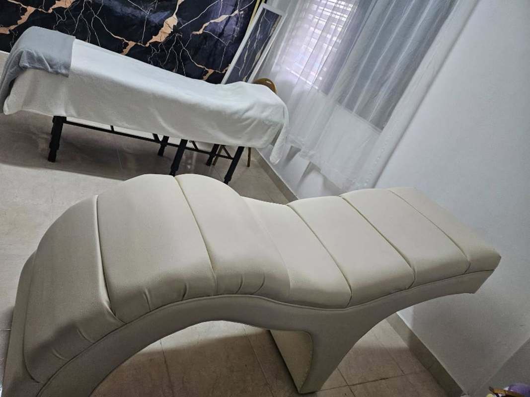 Minimalist spa room with massage table, lounge chair and marble wall decor in commercial plaza Panama
