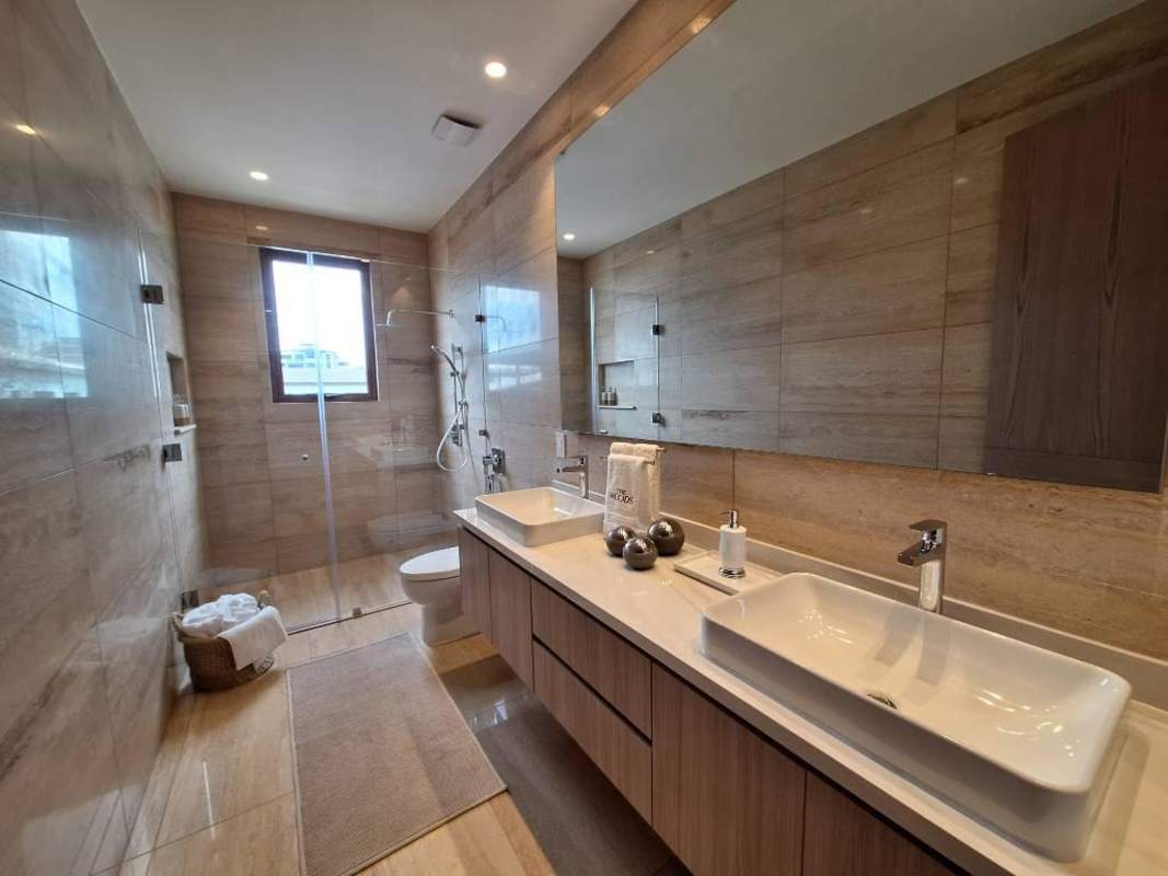 Modern bathroom with double vanities, glass shower and elegant lighting in The Woods Santa María Panama