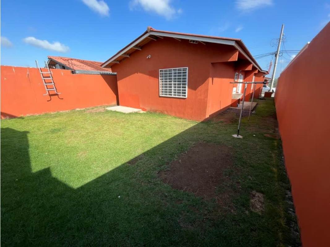 Enclosed backyard lawn with red walls and single-story house PH Colinas del Lago Las Cumbres Panama