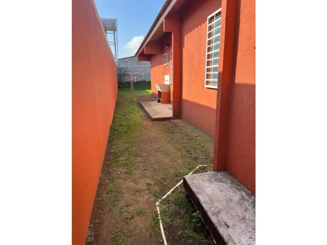 Side yard with orange walls concrete path and outdoor laundry PH Colinas del Lago Las Cumbres Panama