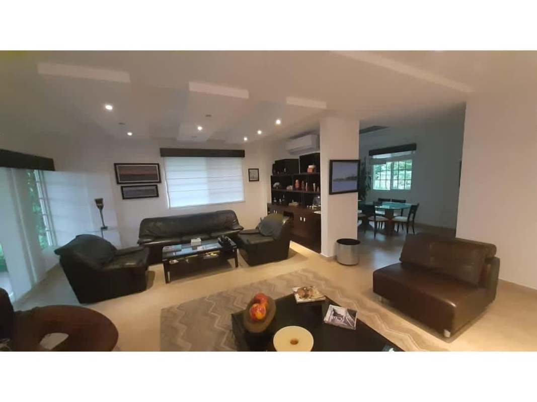 Large built-in bookshelves, beige sofa, workspace and windows in Costa Sur house for sale