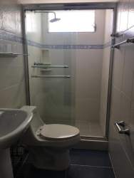Modern bathroom with glass shower enclosure, pedestal sink at beachfront apartment Panama