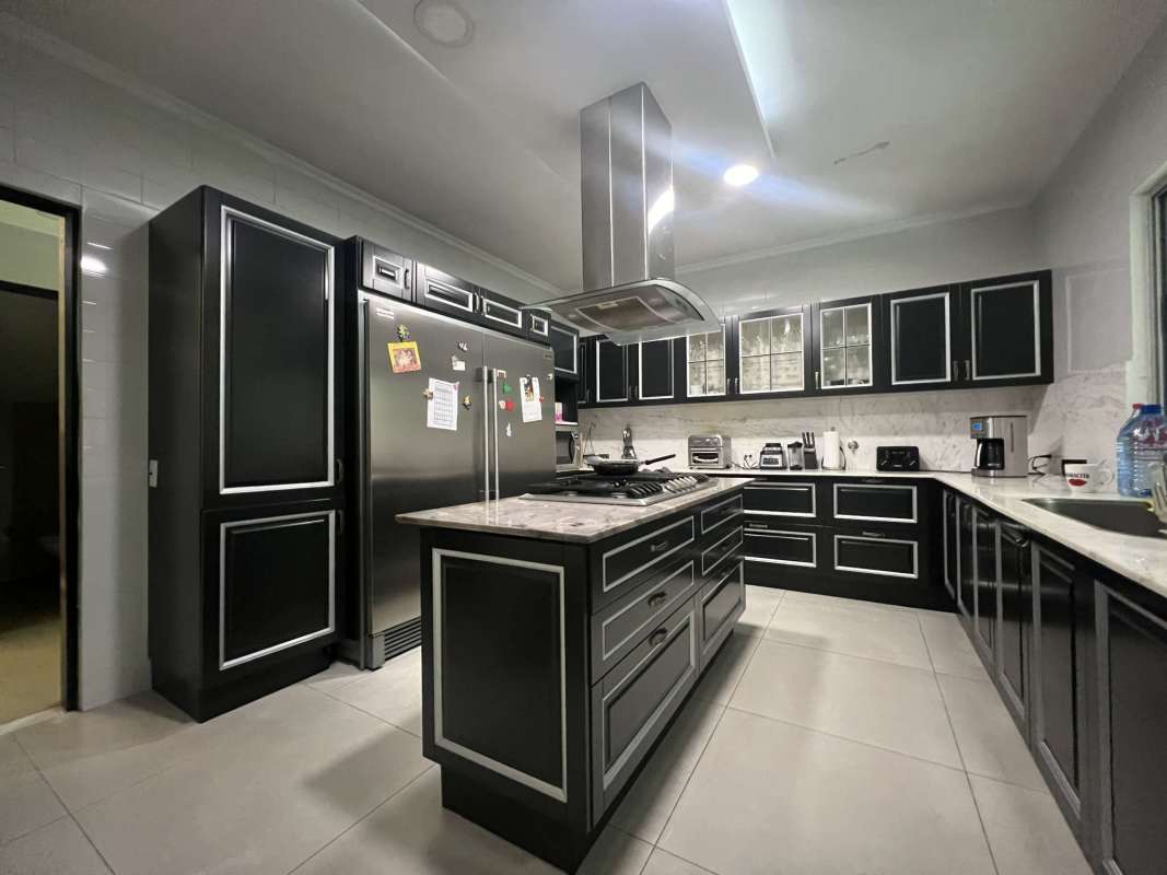 Kitchen with black cabinets, marble countertop island and stainless appliances Dorado Village Panama