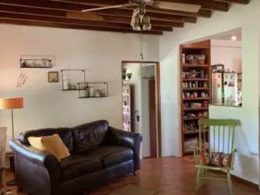 Rustic living room exposed beams black sofa open to kitchen in mountain Panama house