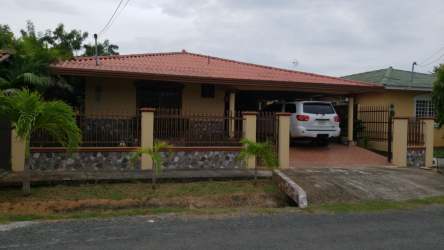 Single story house with red tile roof, carport, fenced driveway in Los Guayacanes Chitré Panama
