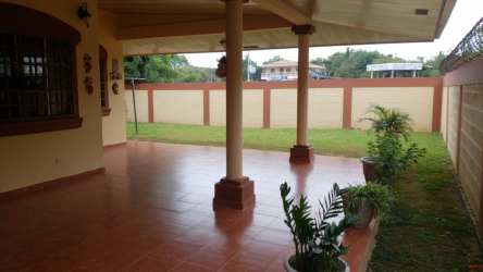 Large covered backyard terrace looking over green fenced yard in Residencial Los Guayacanes Chitré