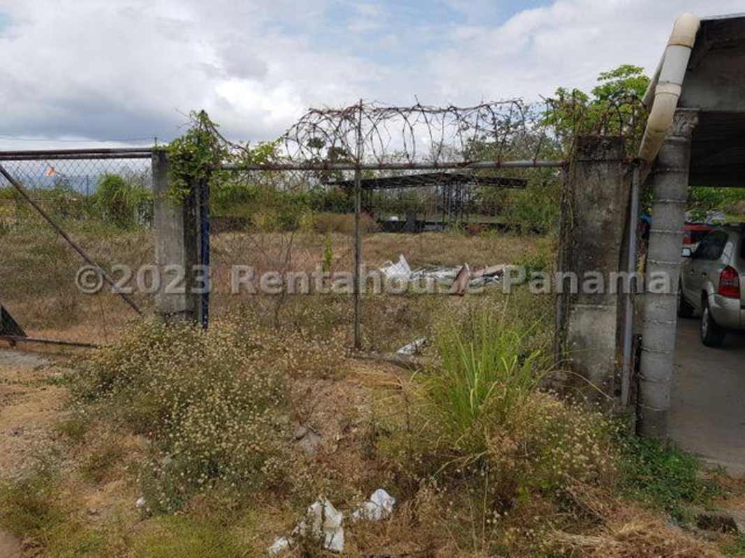 Vacant industrial lot with fencing, concrete posts and parked vehicles Panama