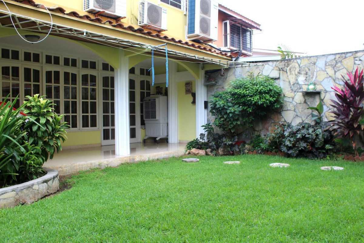 House exterior with covered patio, garden, AC units, yellow facade Betania Panama