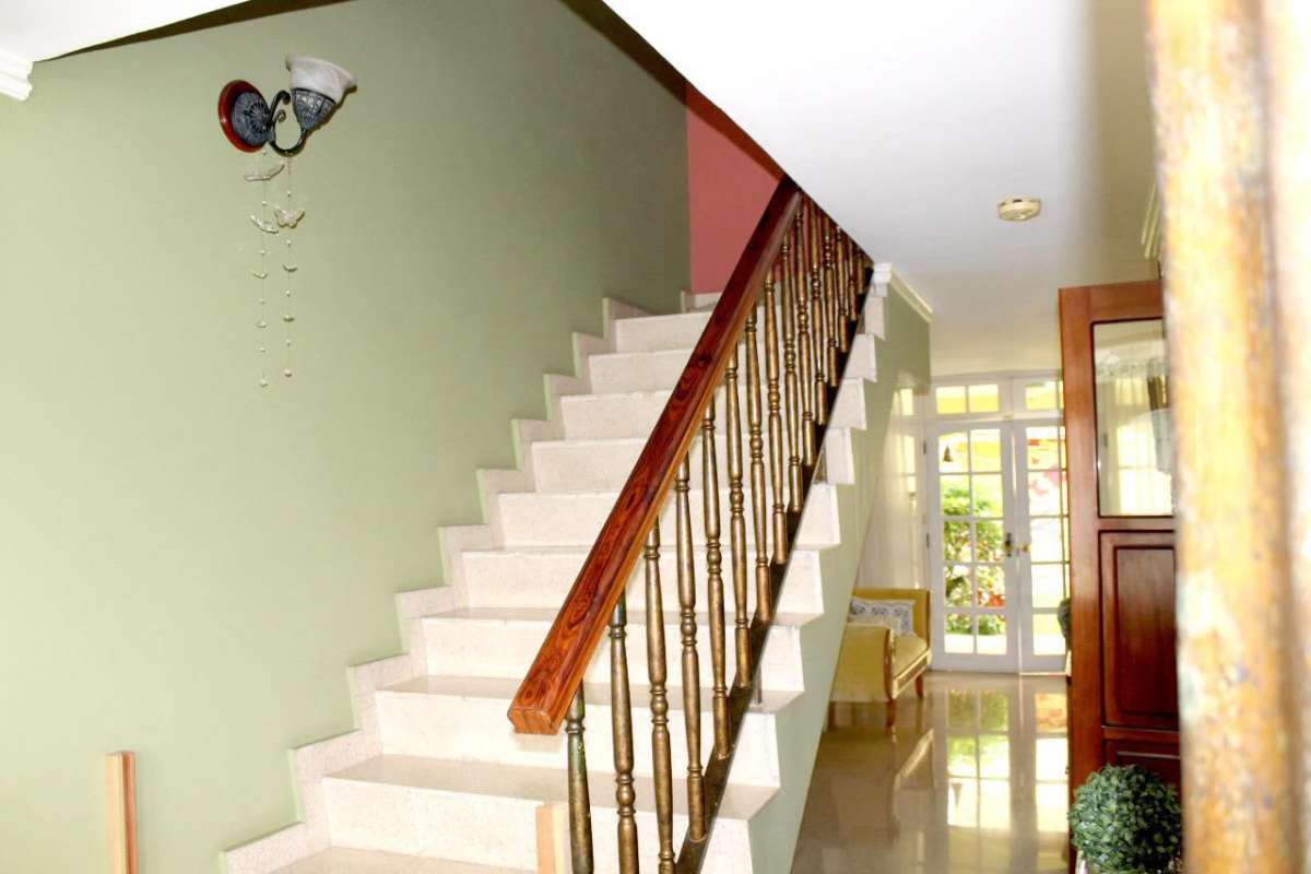 Hallway with glass door, wooden stairs, and green walls in Betania Panama City