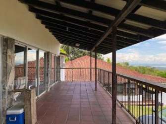 Terracotta floor balcony with exposed beams and glass doors at mountain estate