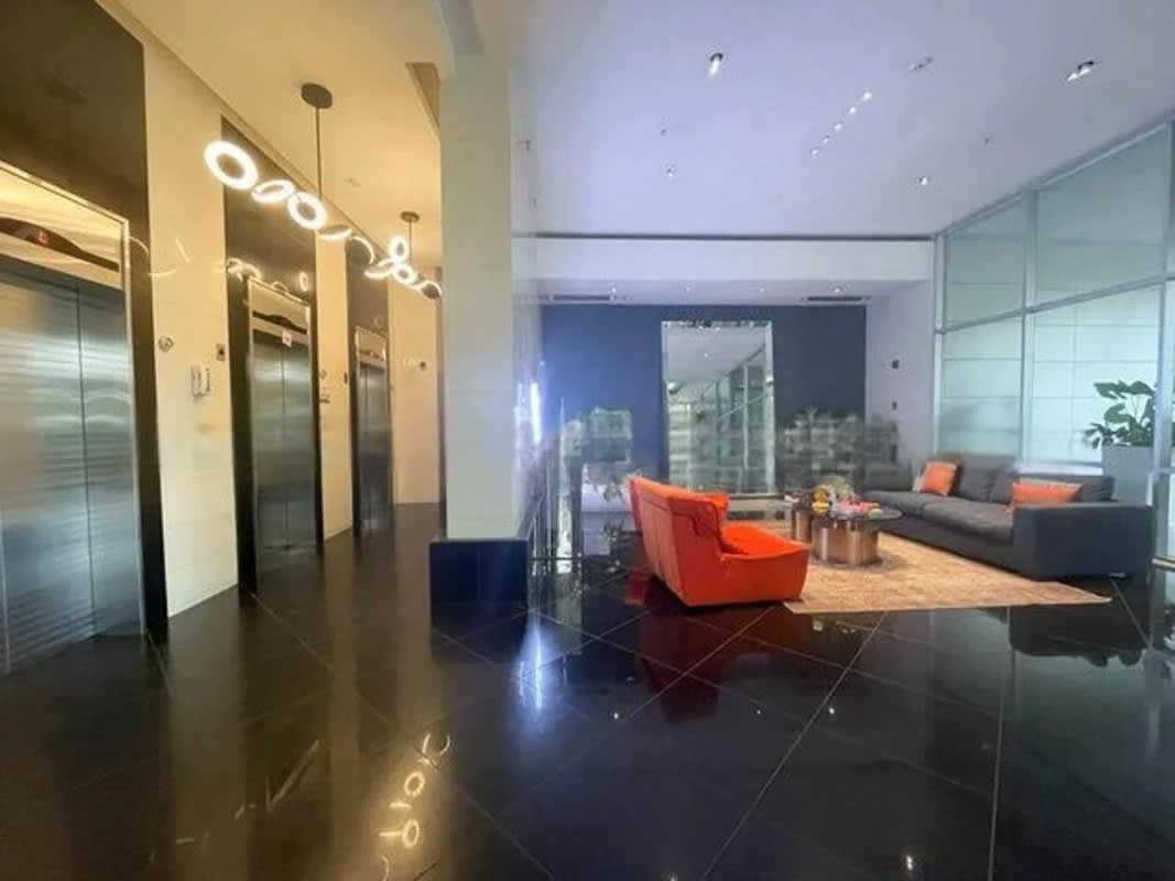 Modern building lobby with reception desk, lounge seating and elevators