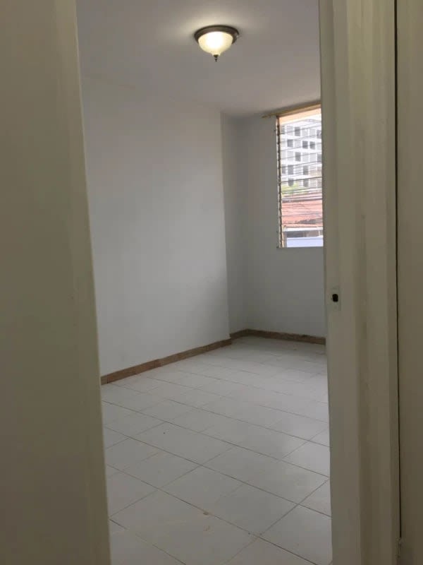 Minimalist bedroom with white walls, tiled floor, window with bars in PH D'LIGHT San Francisco Panama