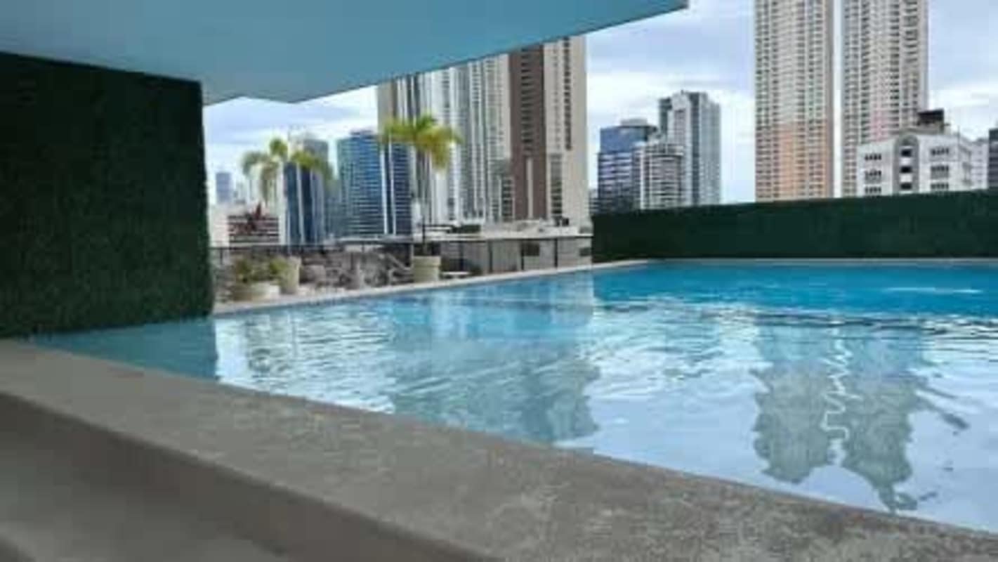 Children's play area on rooftop with colorful equipment and city skyline at PH Calle 50 Panama
