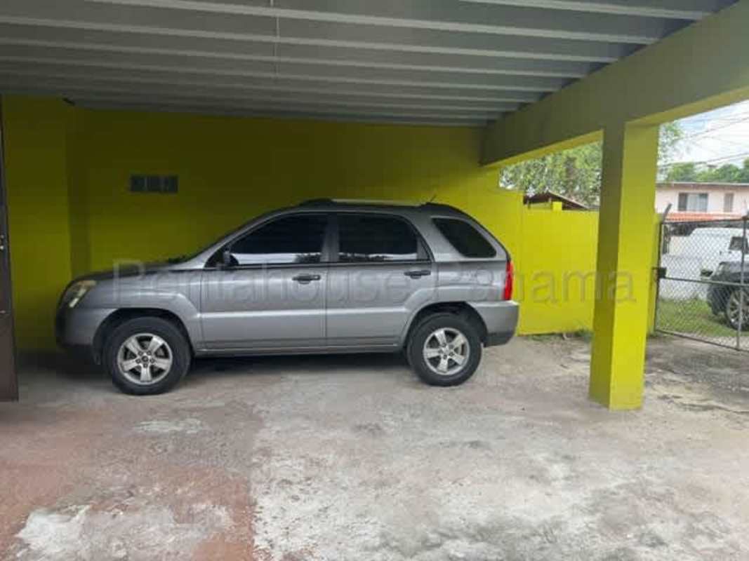 Covered garage area with space for three vehicles and bright yellow facade Rio Abajo Panama