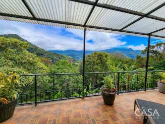 Front elevation of mountain house with gravel drive, arched entryway, and lush green landscaping in Boquete Panama