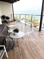 Large beachfront balcony with glass railing, tile floors, ocean and pool views in Playa Escondida condo Panama