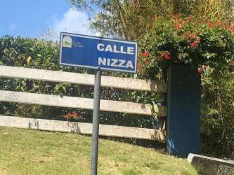 Street sign Calle Niza with landscaped fence and trees in residential mountain community Altos del María Panama