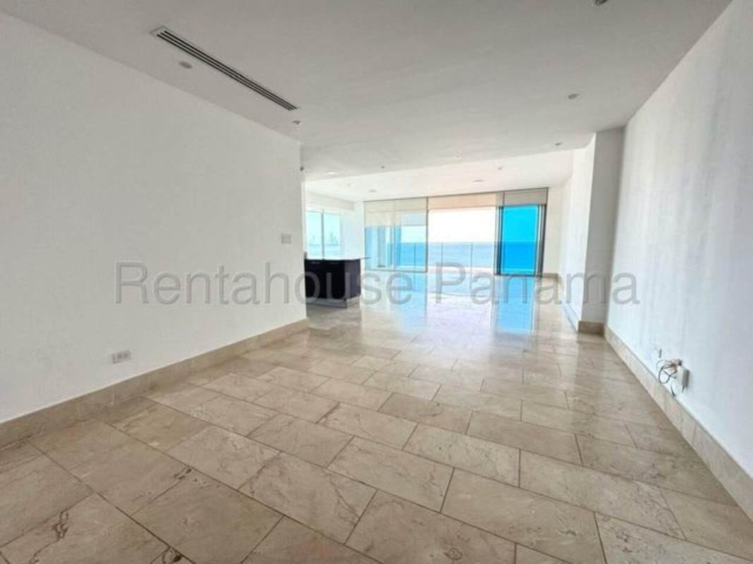 Modern marble-floored living room with floor-to-ceiling windows and balcony access overlooking the Pacific Panama City