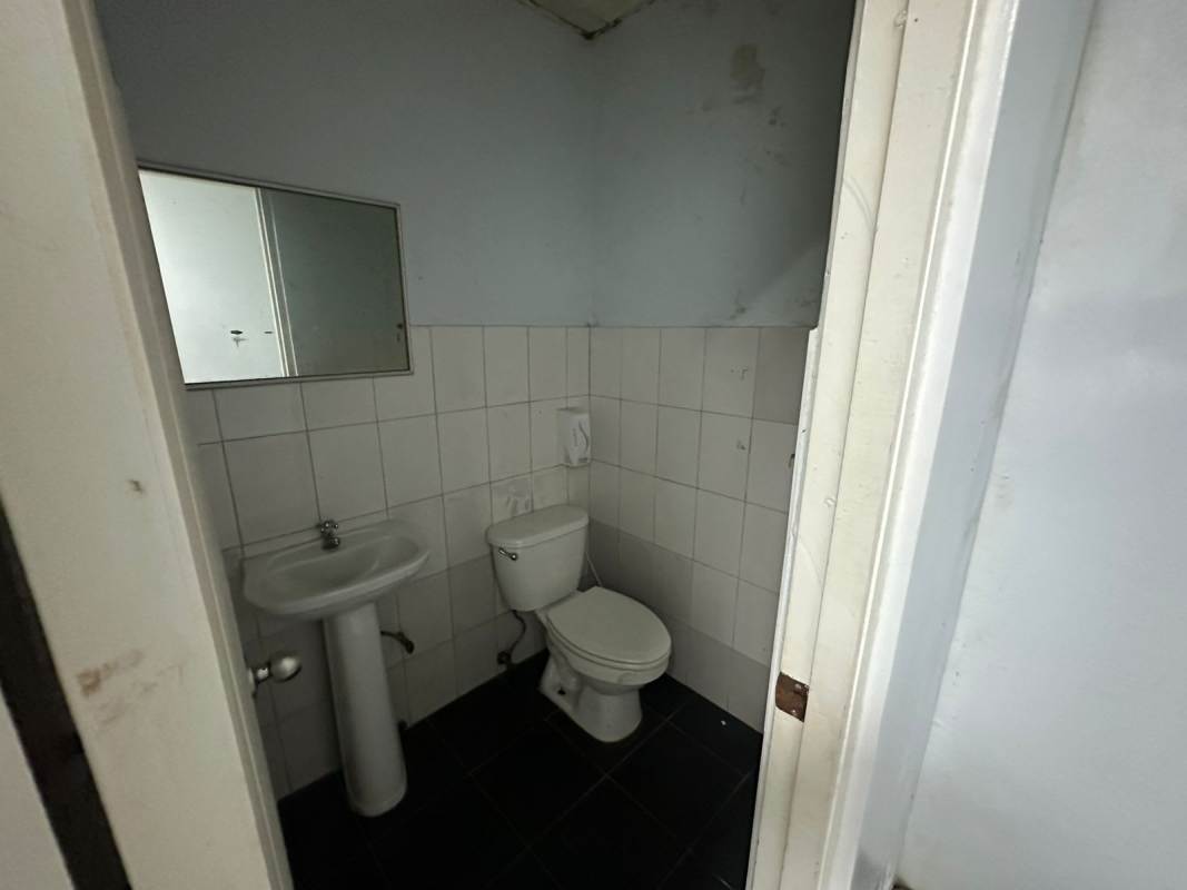 Compact bathroom with pedestal sink and tiled walls inside Pancanal Plaza commercial space Albrook