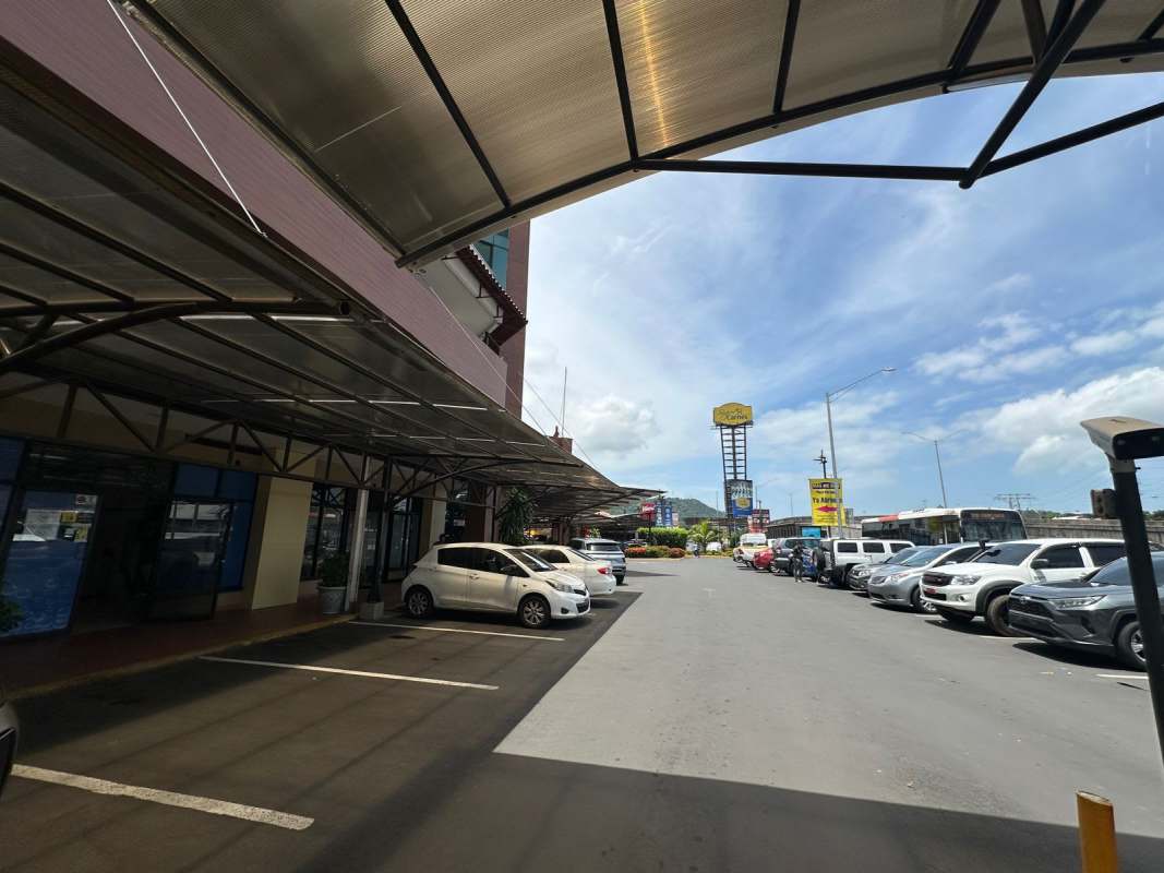 Large parking lot with storefronts and covered walkway in Pancanal Plaza Albrook Panama City