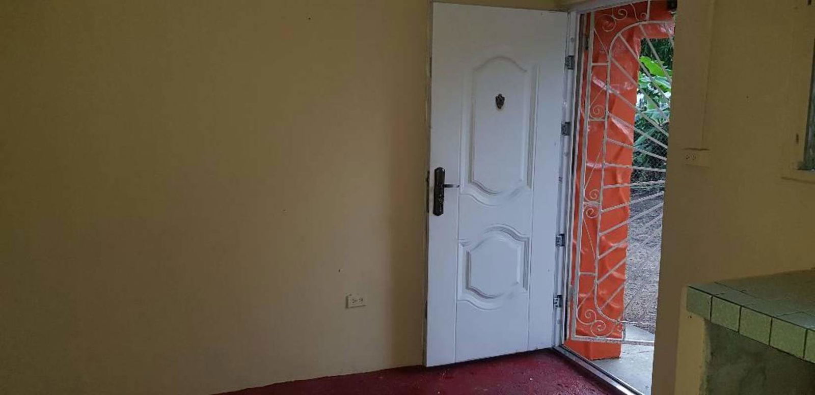Interior entry with open door showing orange patio gate and outdoor garden