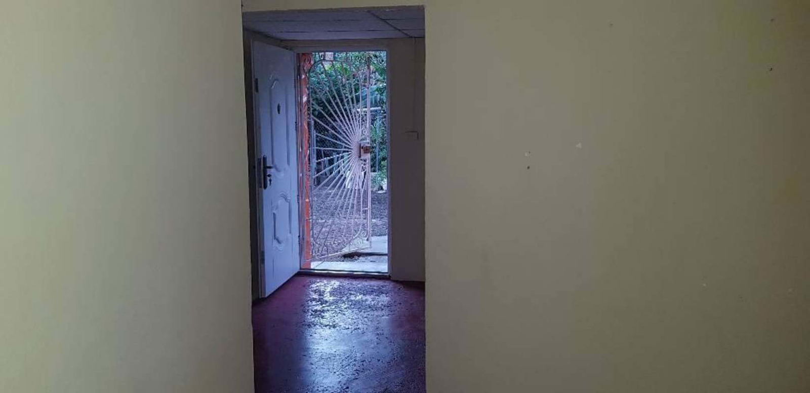 Simple entryway interior with white door and orange security grill 24 de Diciembre