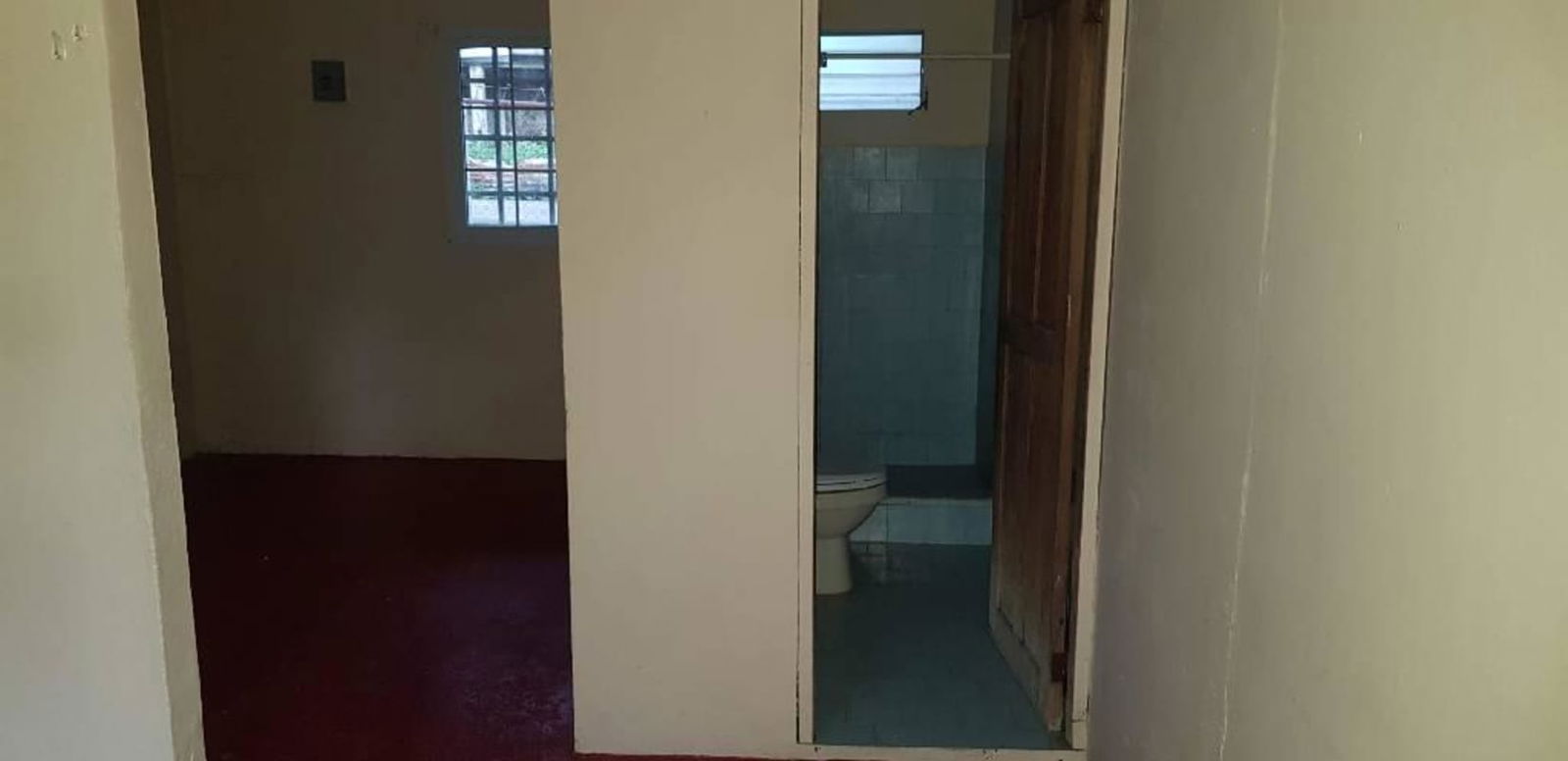 Simple bathroom with toilet and window security bars Panama rental