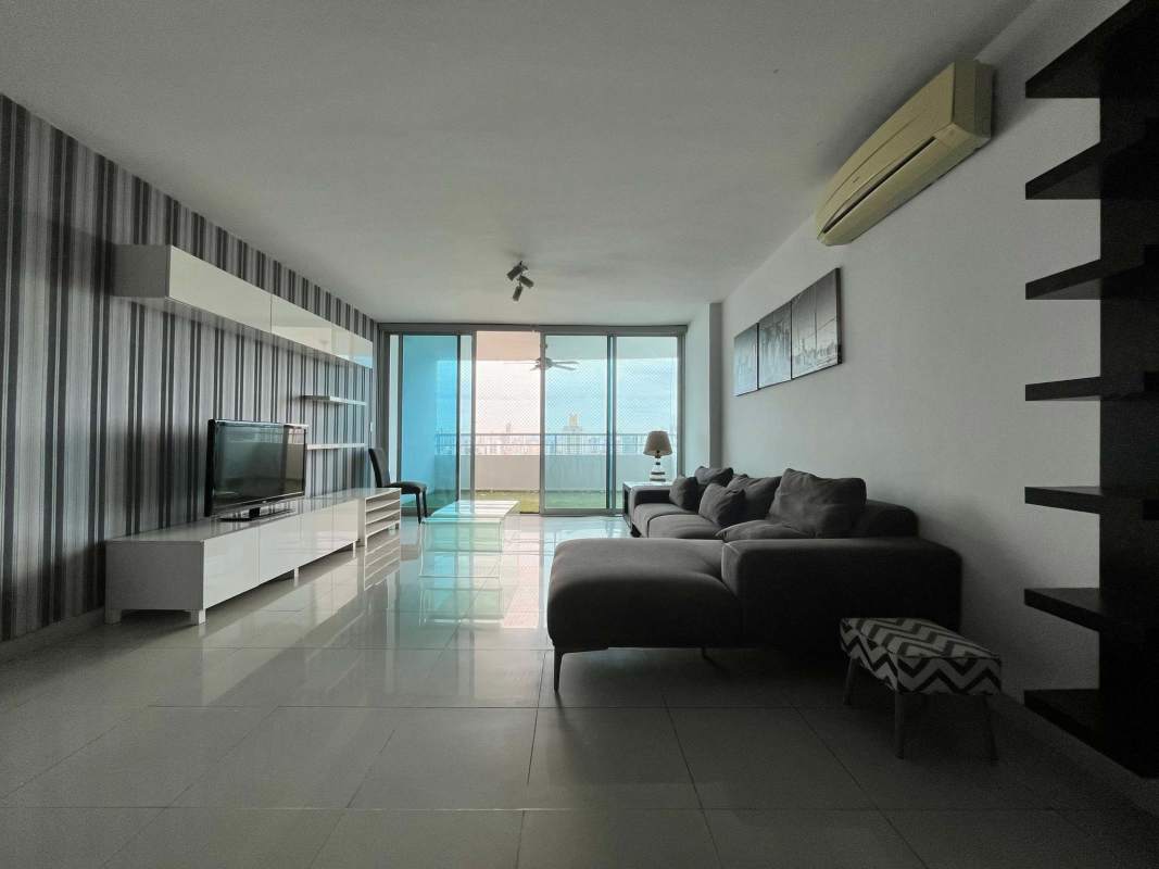 Modern living room with sectional sofa, balcony access, and skyline views in PH Titanium Panama City