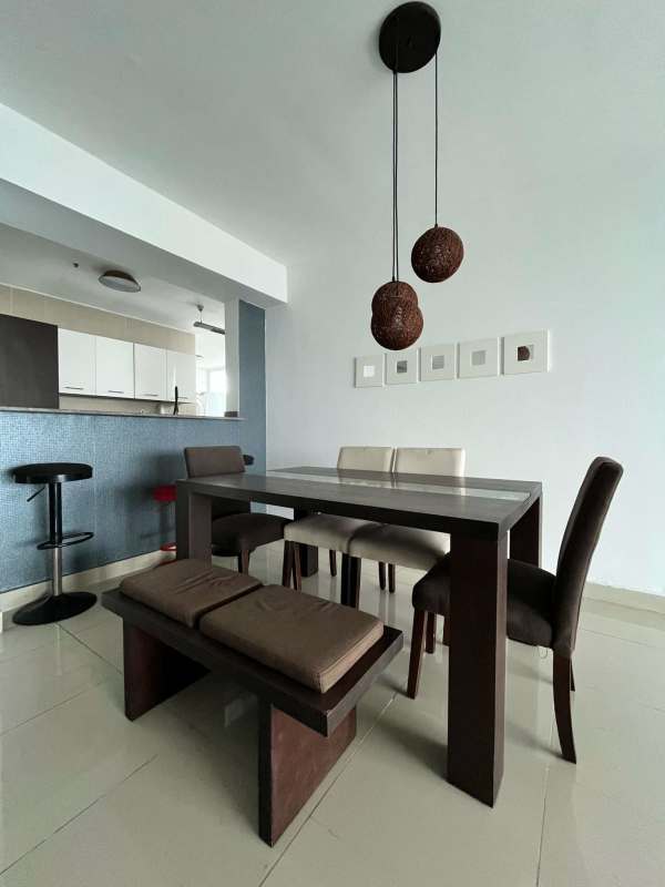Modern dining area with glass table, pendant lighting, and breakfast bar view in PH Titanium Panama City
