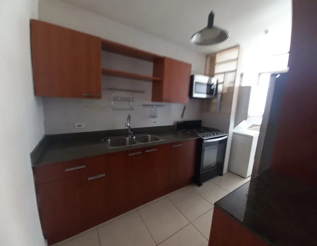 Modern kitchen with wood cabinets black counters seen through open doorway PH San Francisco Bay Panama
