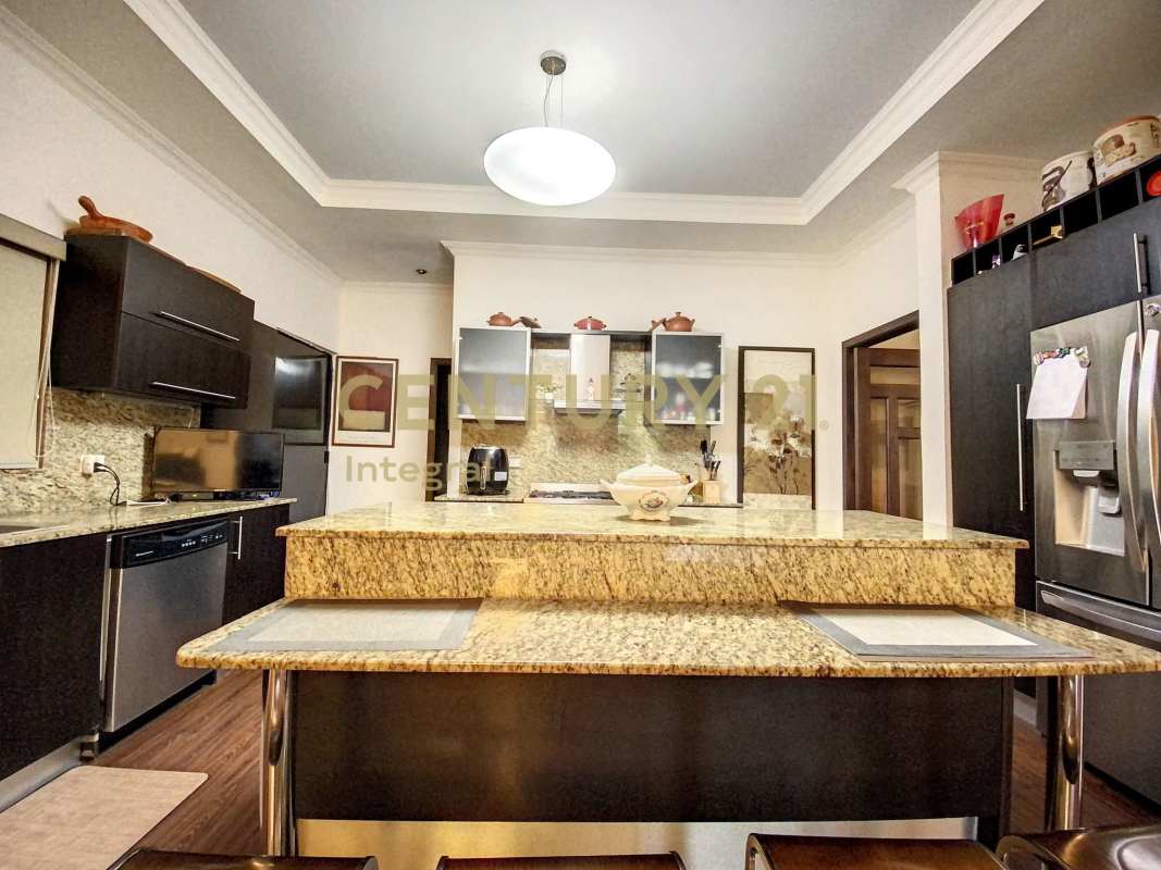 Spacious kitchen with granite island, modern appliances, and dark cabinetry in PH Sunset Coast Costa Sur Panama