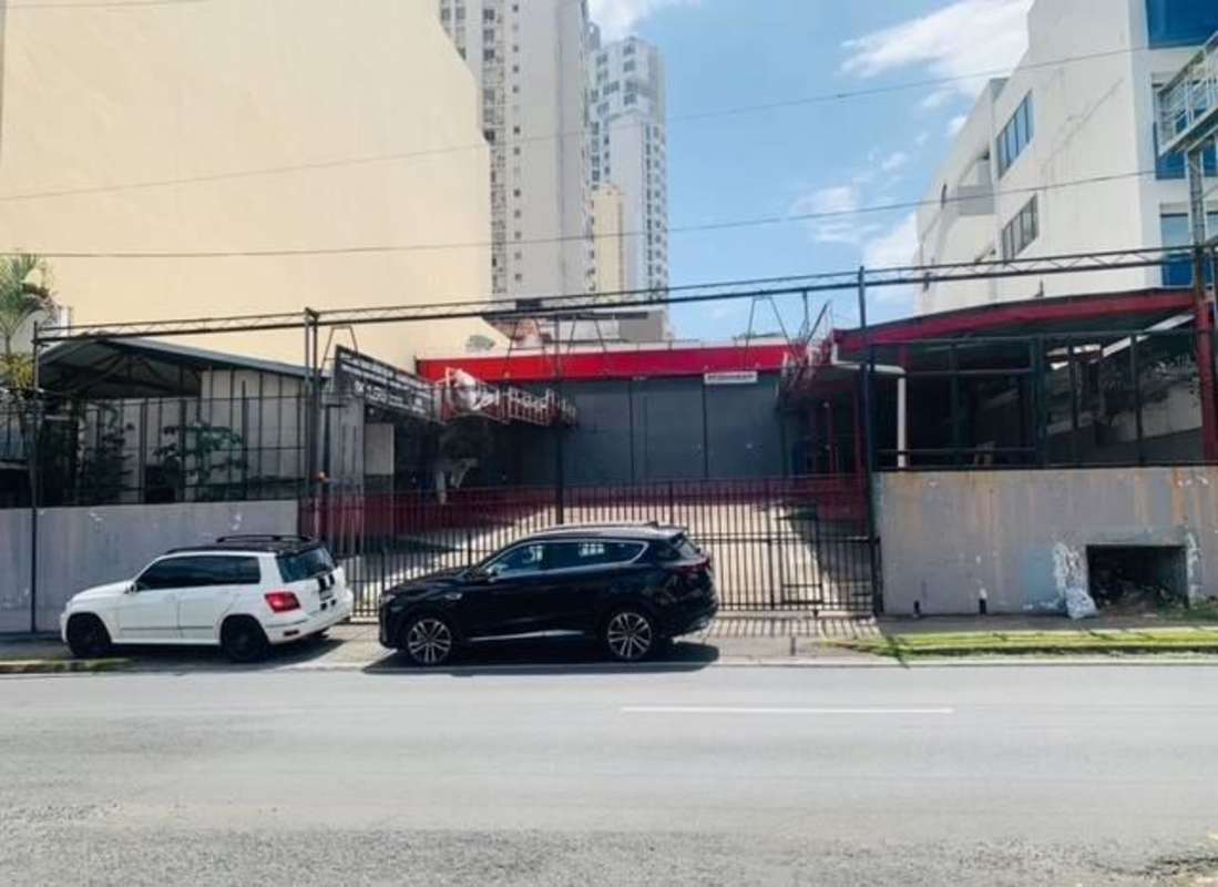 Exterior of streetfront commercial warehouse building with security gate glass storefront and parking in 12 de Octubre Panama City