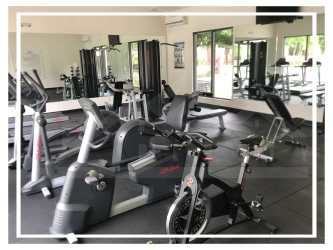 Modern bedroom with mounted TV, ceiling fan, and minimalist decor in PH Midrise Panama Pacifico