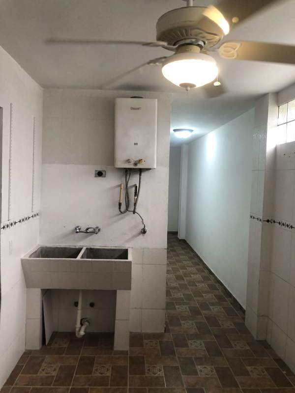 Laundry area with utility sink and tiled walls in duplex Panama City