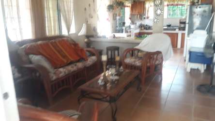 Traditional living room with open kitchen, tiled floor, wood furniture and large windows in Gorgona Panama