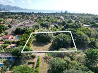 Drone photo of vacant ocean-close lot bordered by trees within gated community in Coronado Panama