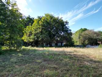 Partly hidden white home with trees in Coronado Panama near ocean lot for sale