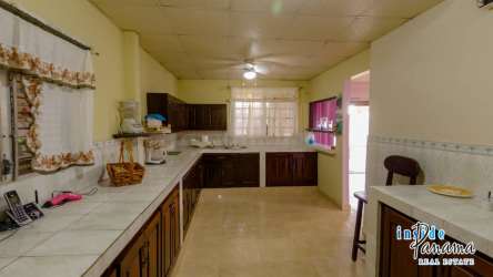 Large kitchen with wood cabinetry tile counters ceiling fan in guesthouse Pocri Pedasi Panama