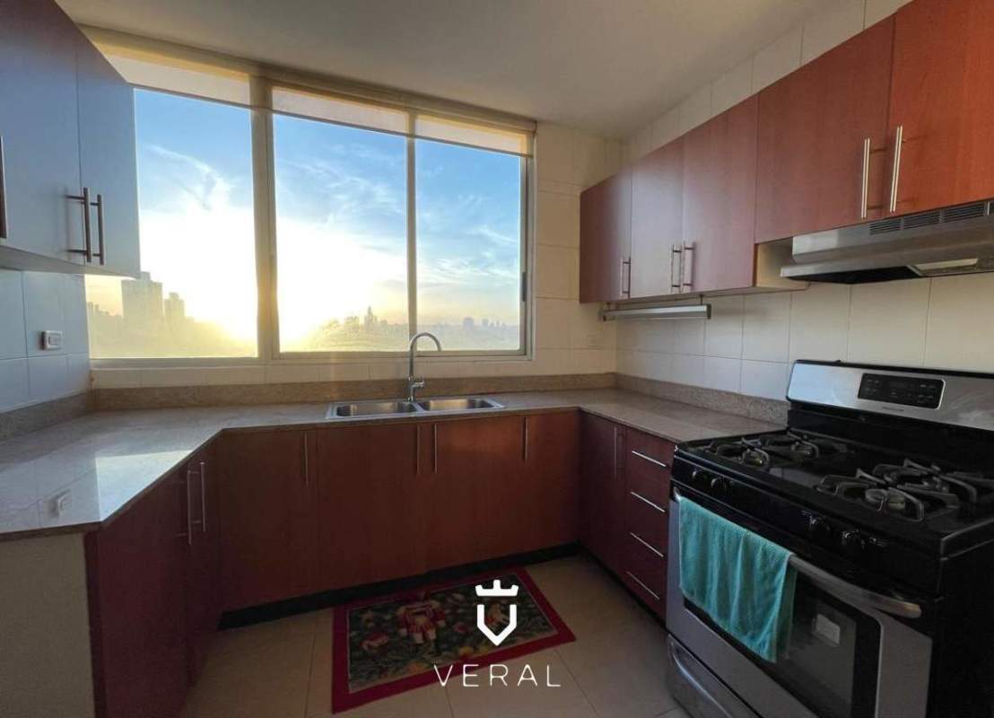 Spacious kitchen with granite countertops, wood cabinetry, city views in PH Veranda Tower Panama City apartment