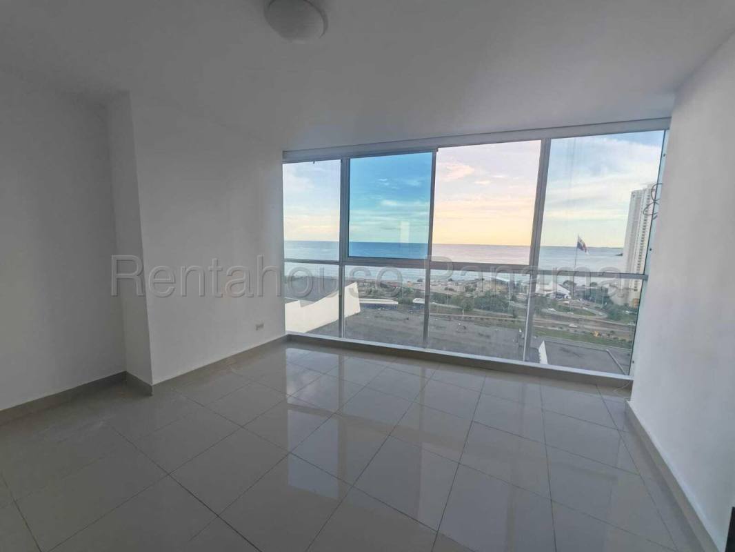 Bright minimalist living room with glass walls overlooking ocean in Serenity at the Bay
