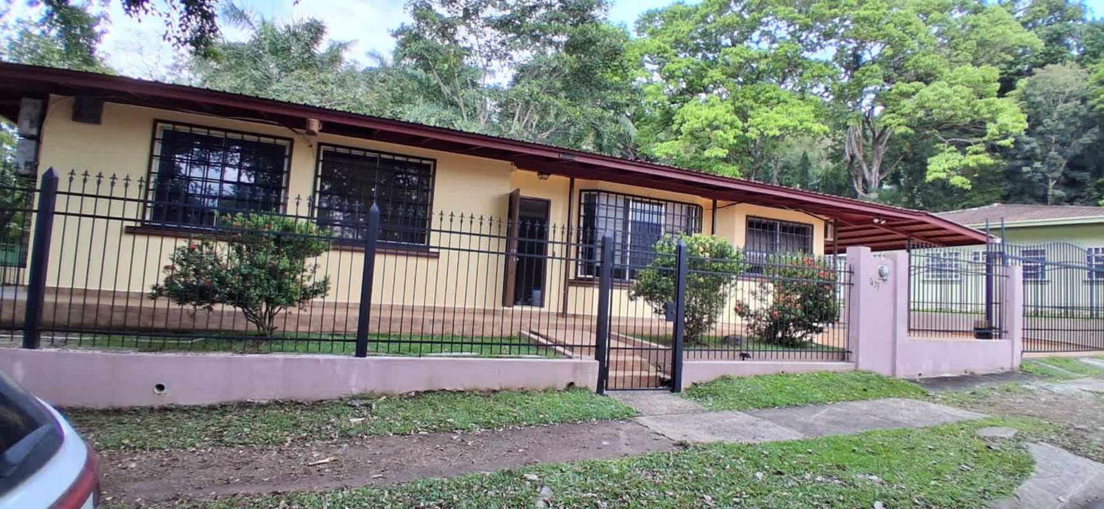 Exterior view yellow house red roof metal fence carport garden Balboa Canal Zone Panama