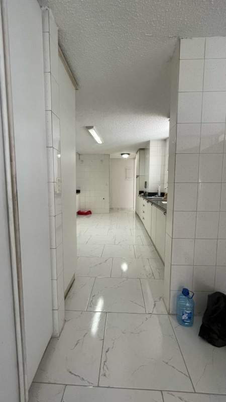 Long kitchen with black countertop natural light marble tile floors PH Tamanaco Panama City