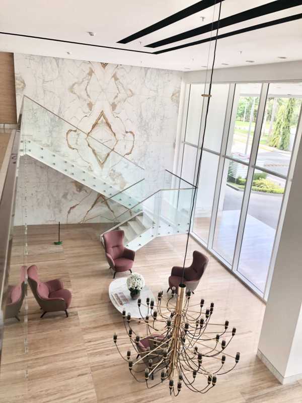 Modern lobby interior with glass stairs, marble wall, pink sofas at PH Paramount Costa del Este Panama City luxury tower