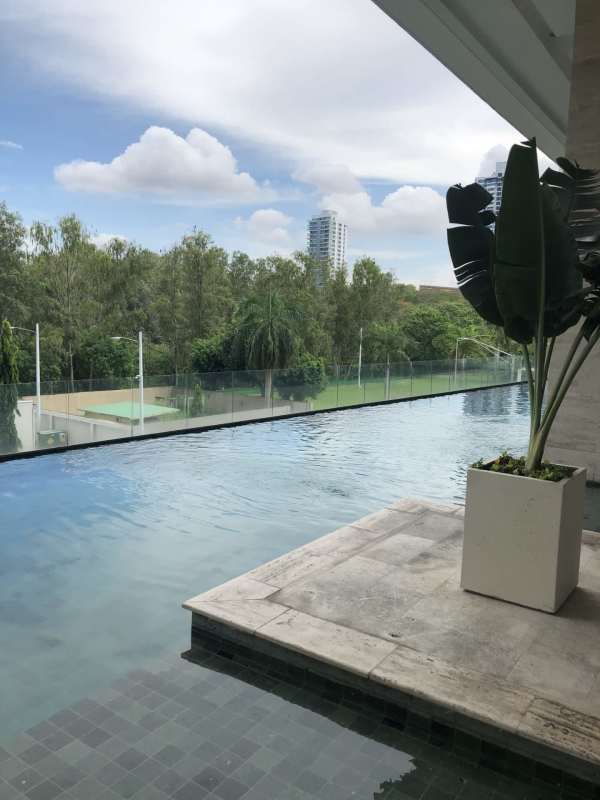 Infinity pool on deck with views of Panama City skyscrapers and greenery at PH Paramount Costa del Este