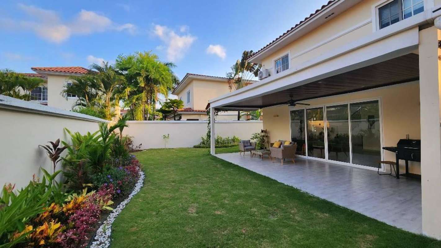 Covered patio with outdoor wicker seating and landscaped yard Costa Sur Panama