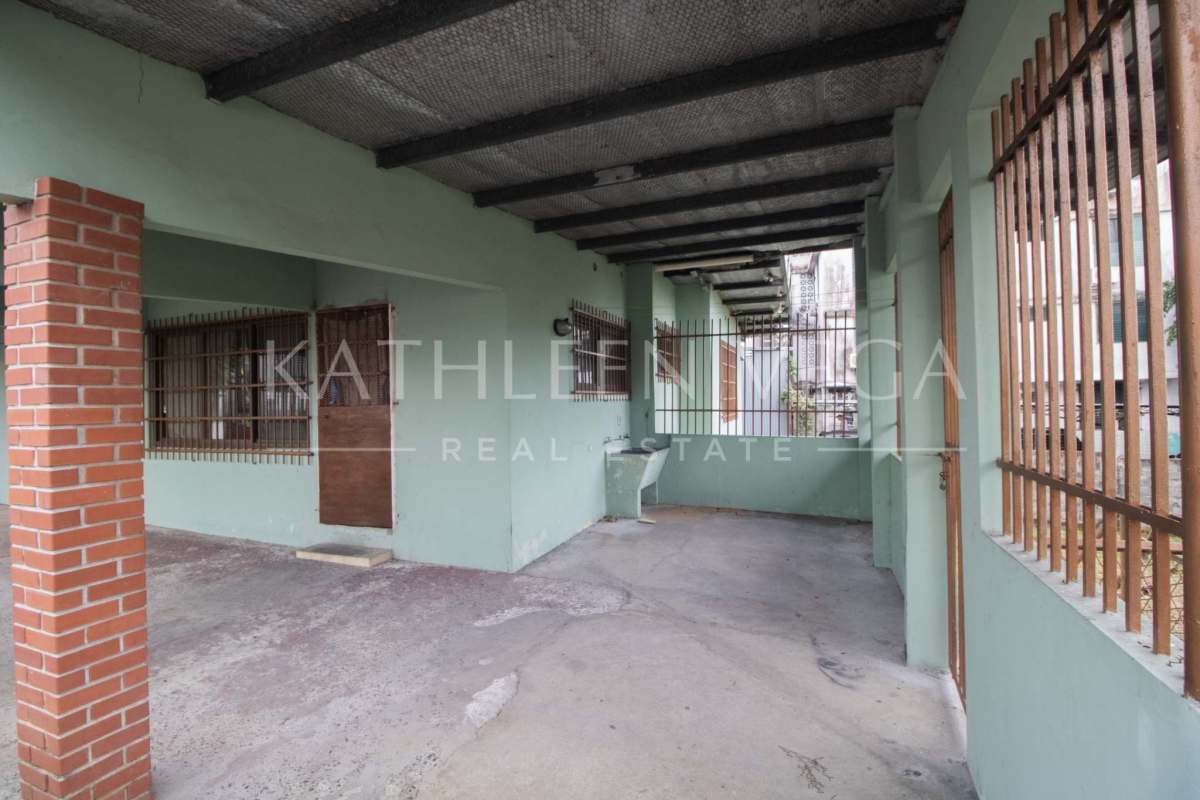 Front fenced yard with brick pillars, grilled windows, covered porch of house Carrasquilla Panama