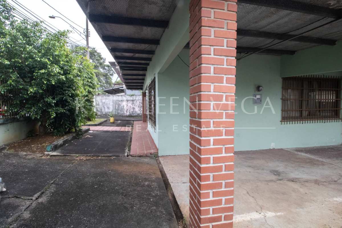 Traditional home with brick columns, metal roof, and covered gated driveway in Carrasquilla Panama City